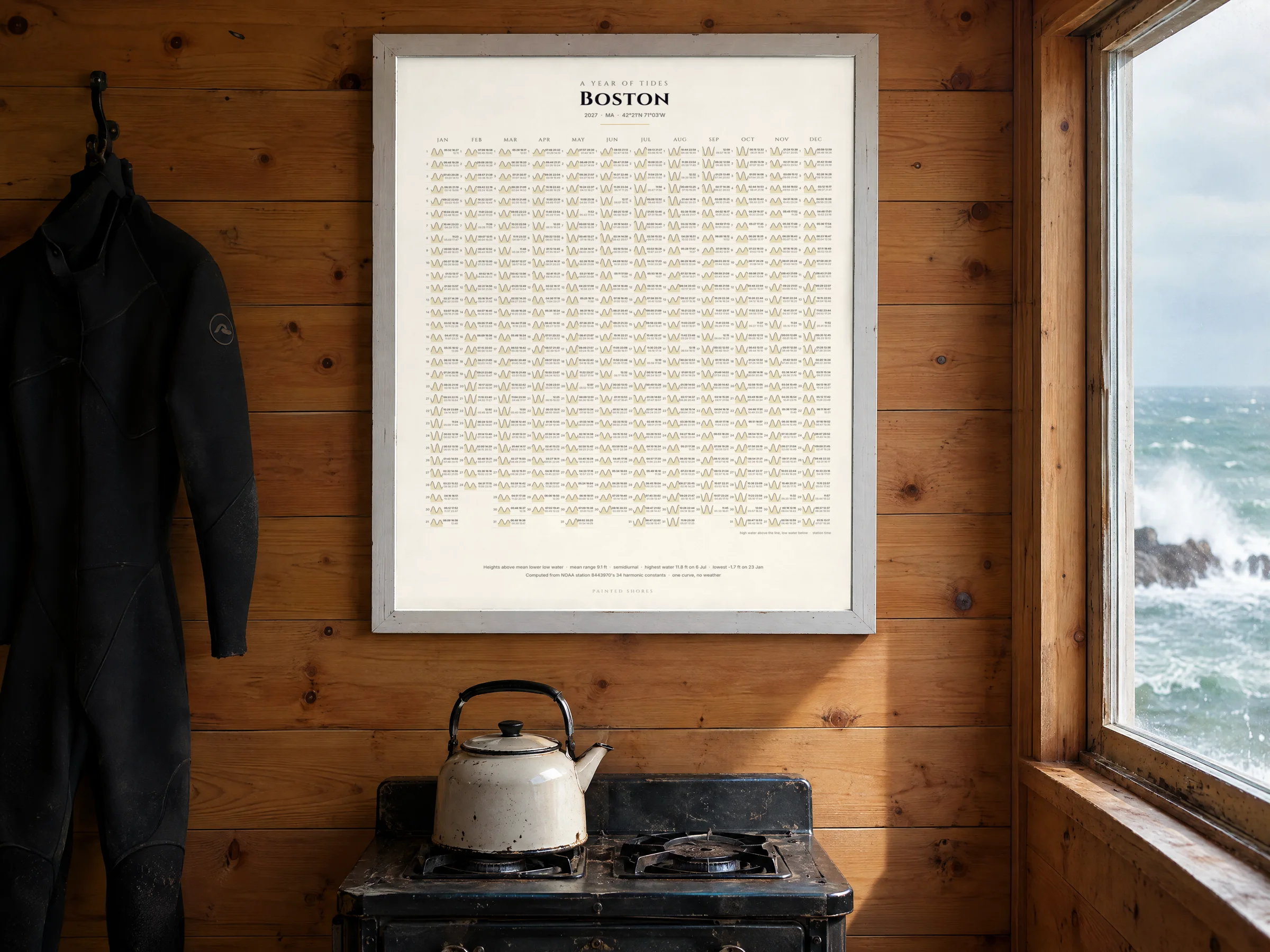 The tide calendar of San Francisco's year in a white frame on the pine wall of a surf cabin, a wetsuit on a hook beside it and a kettle below